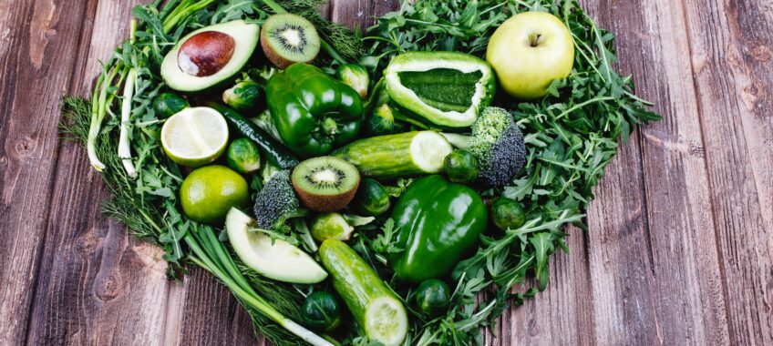 Fresh vegetables, fruits and greenery. Healthy life and food. Broccoli, avocado, apples, broccoli, cabbage and green onion served on rustic wooden table. Heart form